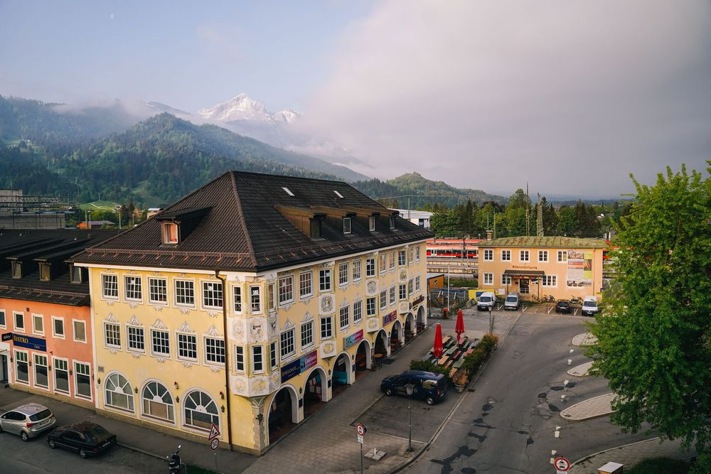 Panoramic mountain town view with commercial buildings and storefronts along a street with mountains in the distance.