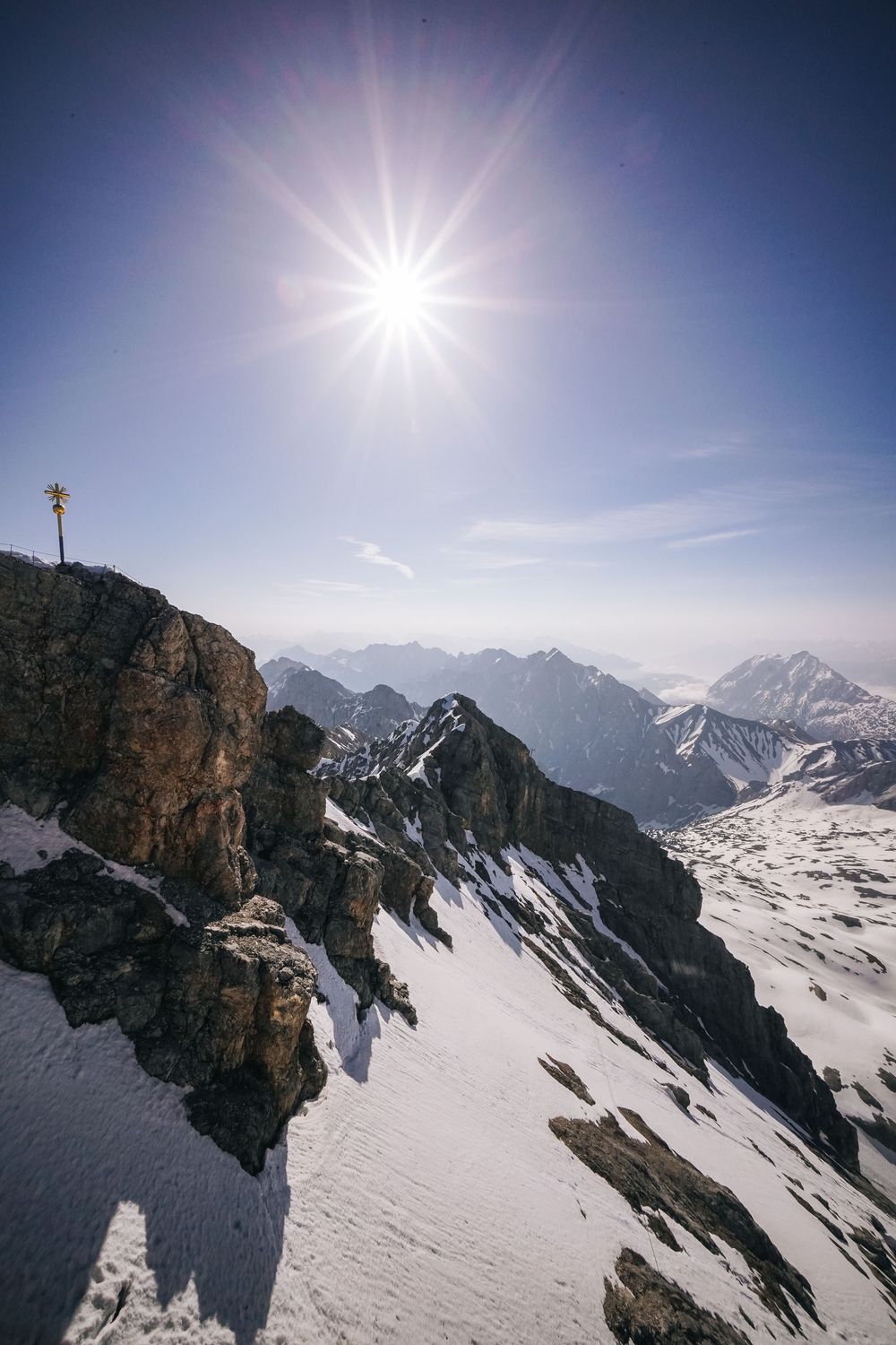 Majestic snow-capped mountains under bright sunlight with rocky cliffs casting shadows on pristine winter landscape.