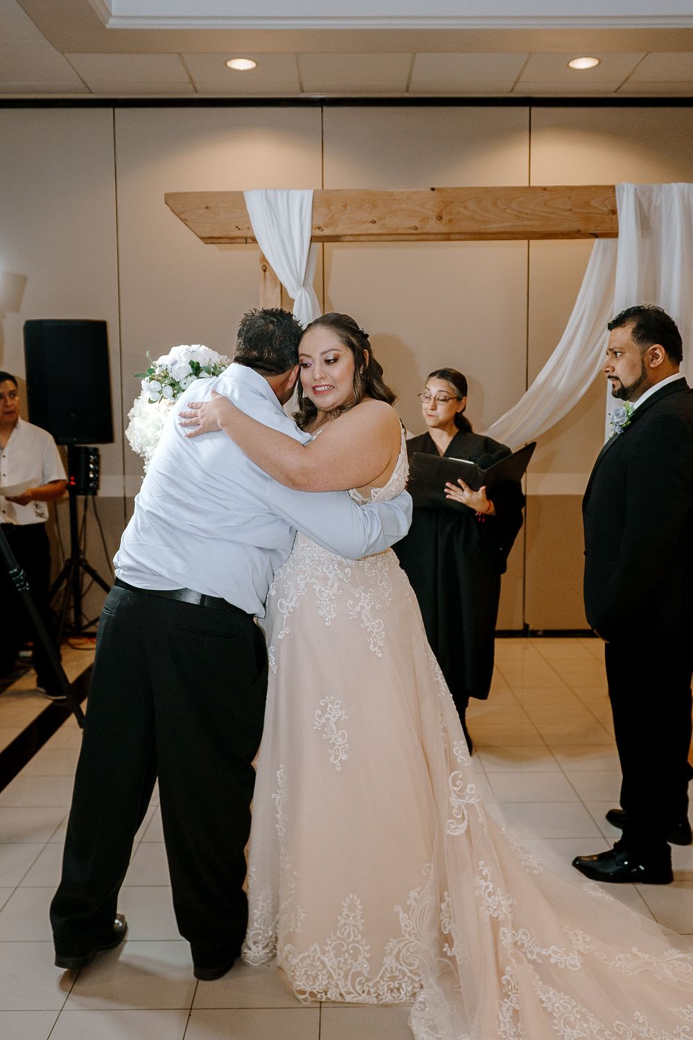A couple shares their first dance at their wedding reception, with the bride wearing an elegant lace gown with a flowing train.