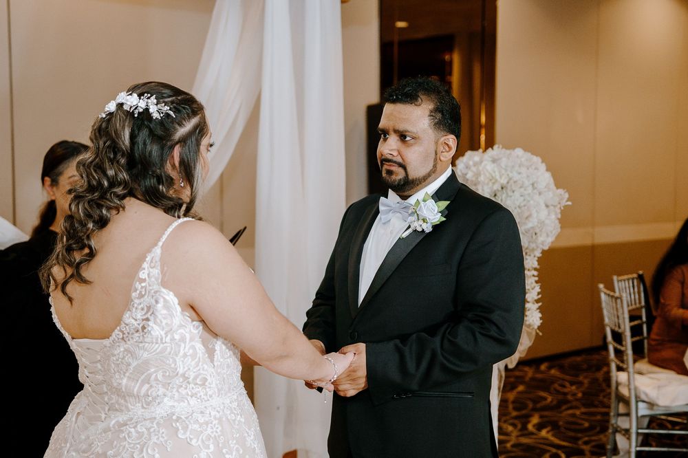 Wedding party toasts with champagne glasses during a celebration at an elegant indoor venue.