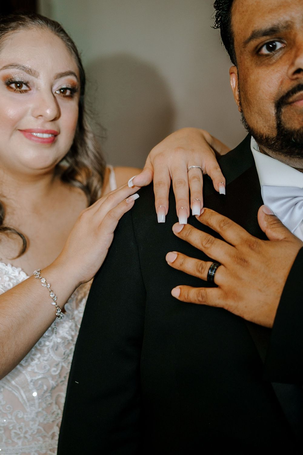 Close-up wedding photo showing hands with rings as newlyweds share a tender moment.