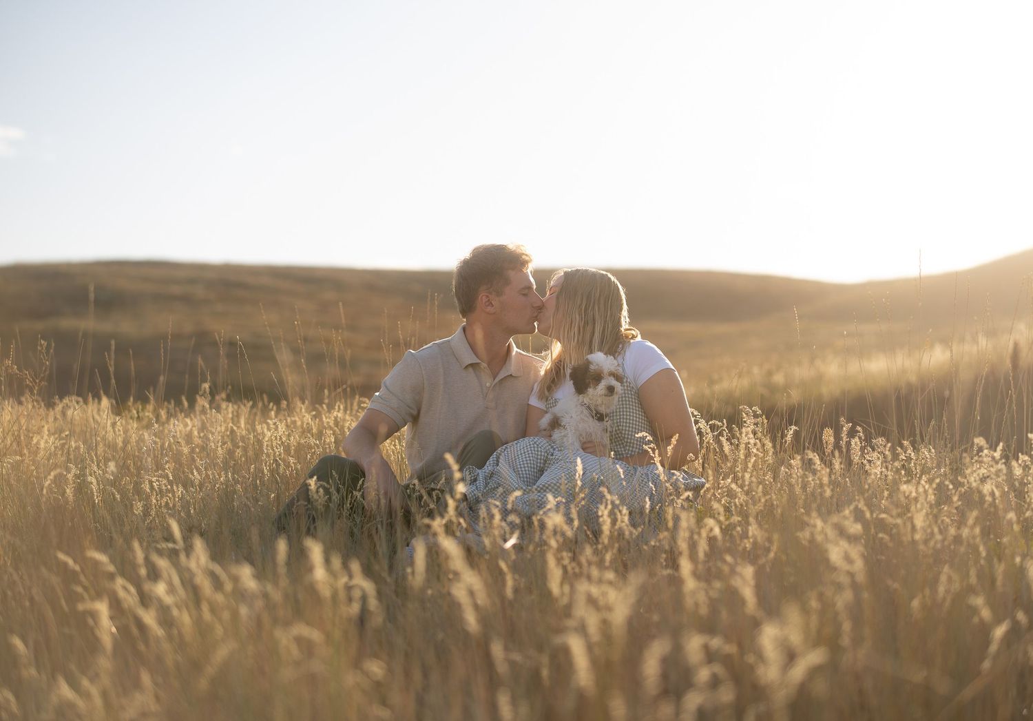 Romantic engagement session portrait of a couple holding each other in a grassy field in Logan, UT.