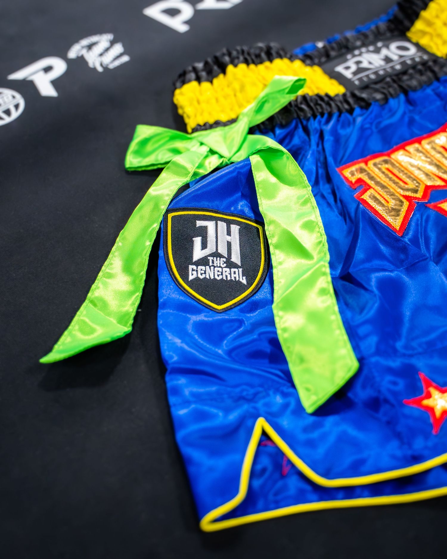 Close-up of blue and yellow wrestling singlet with bright green accents against black surface.
