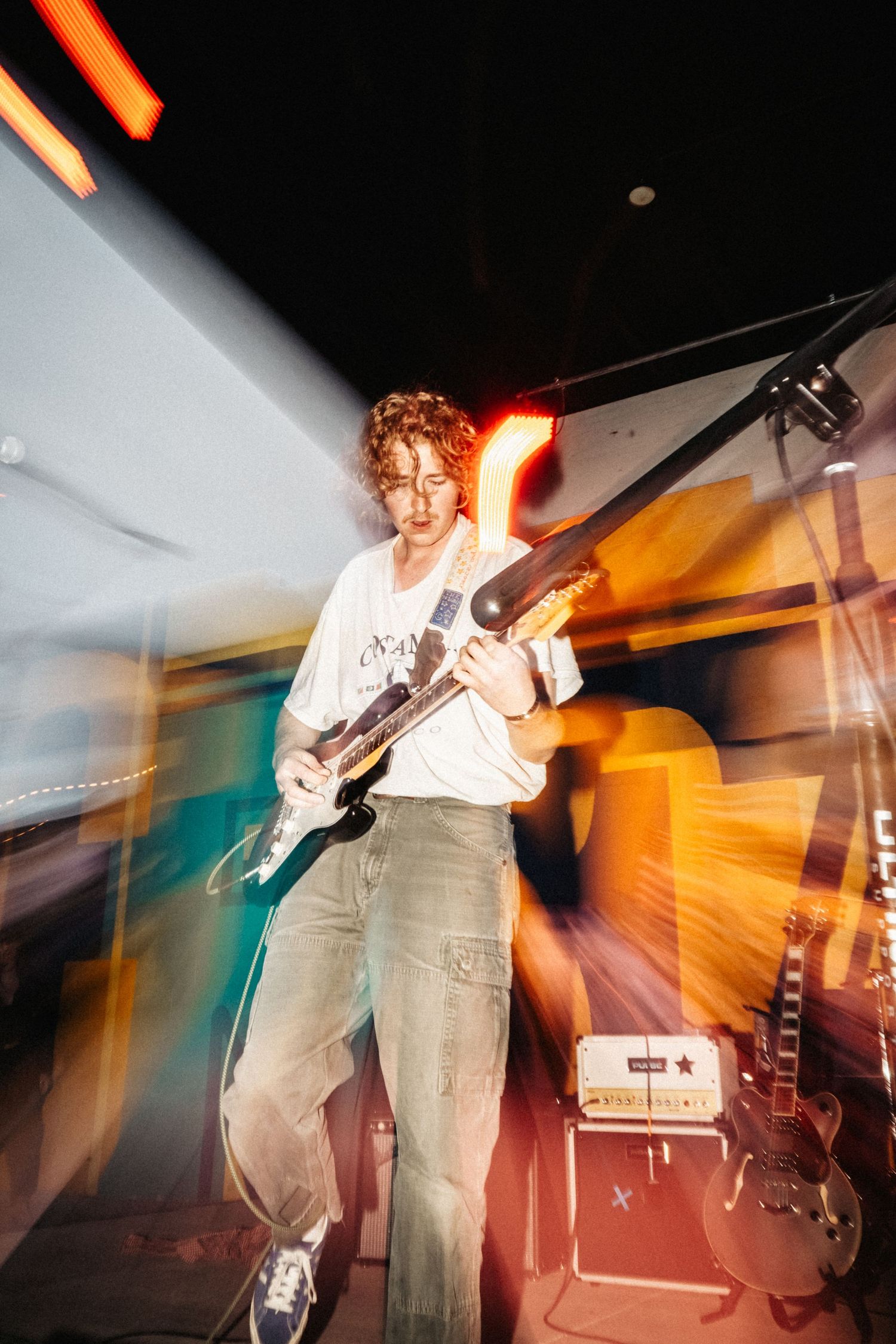 A flash photo of a man playing guitar with streaks of light surrounding him.