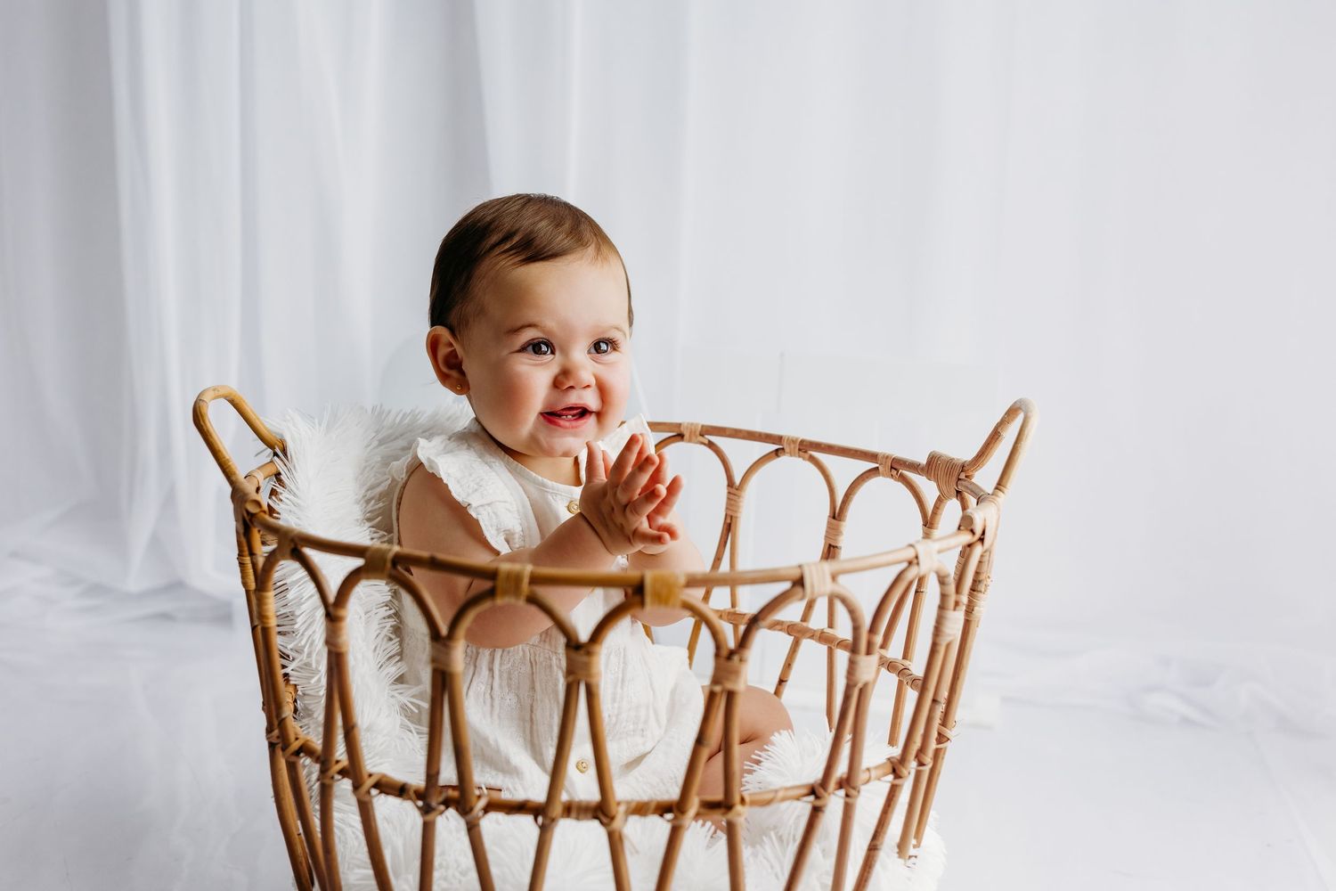 A sequence showing young baby sitting in wicker basket prop against white background for studio photography session.