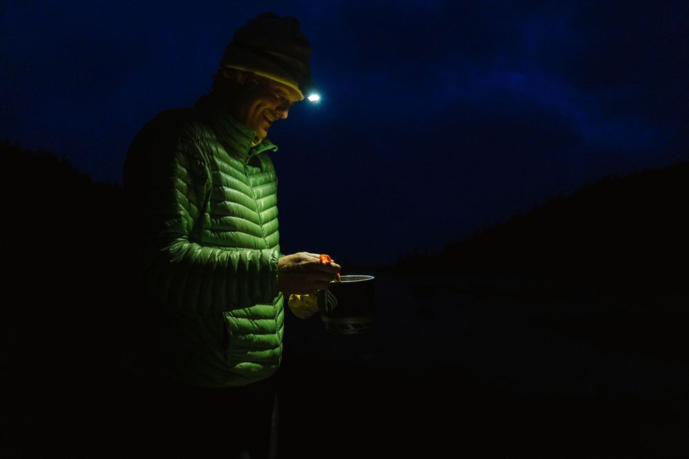 Person using headlamp while camping in dark wilderness setting.