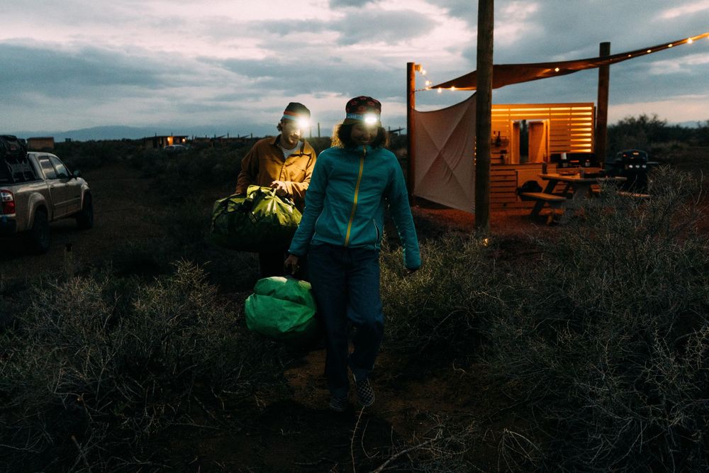 Scenic mountain landscape at dusk with camping equipment silhouetted against the sky.
