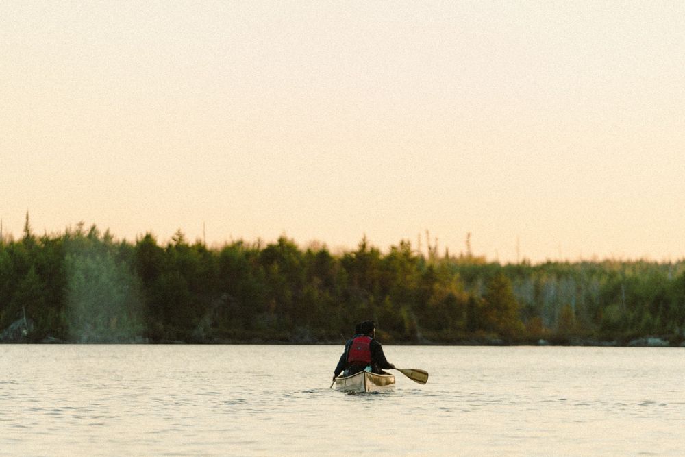 Tranquil lake view at sunset with forest-lined shoreline.