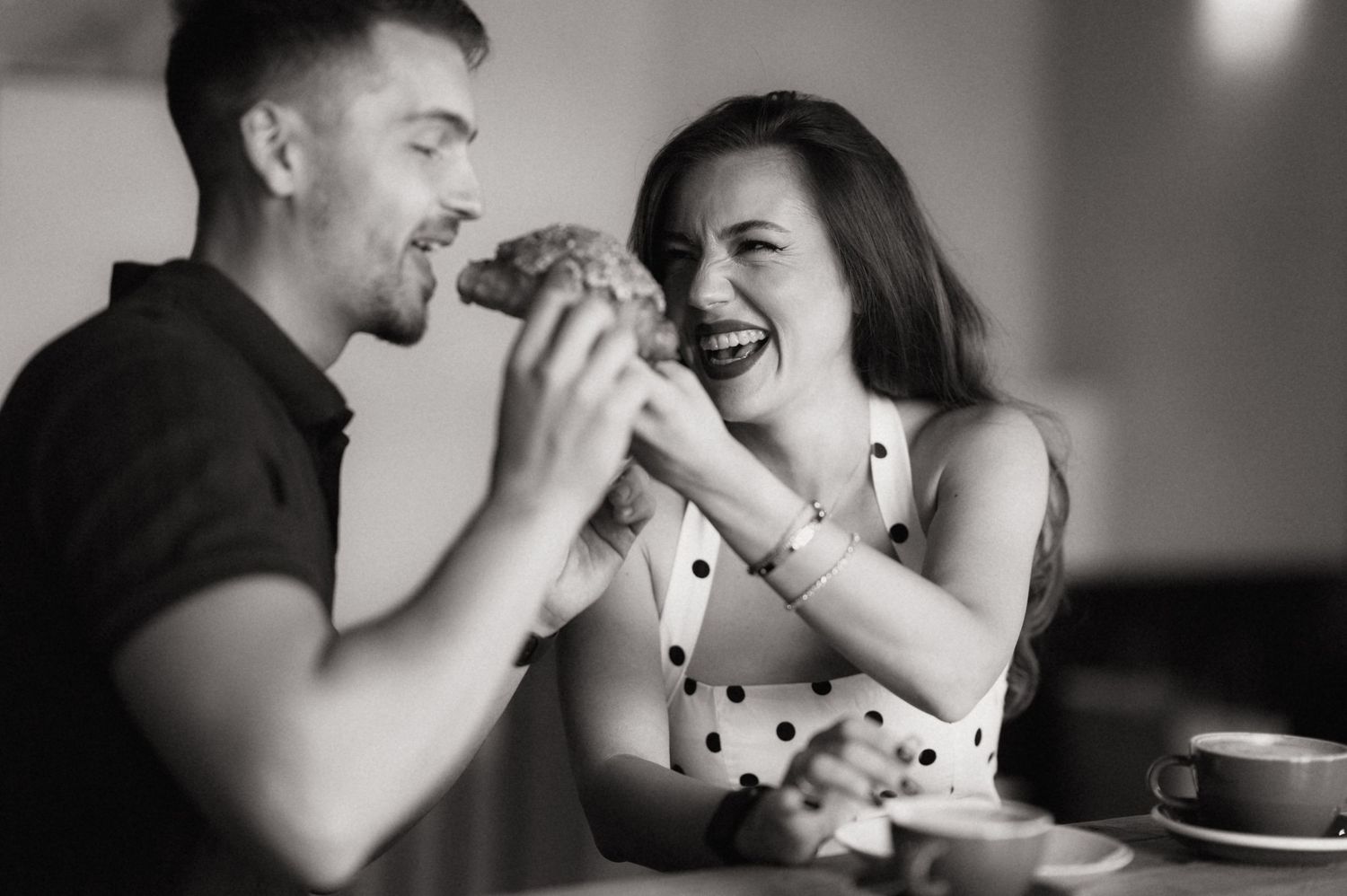 A couple shares an intimate moment while dining together at a restaurant in black and white.