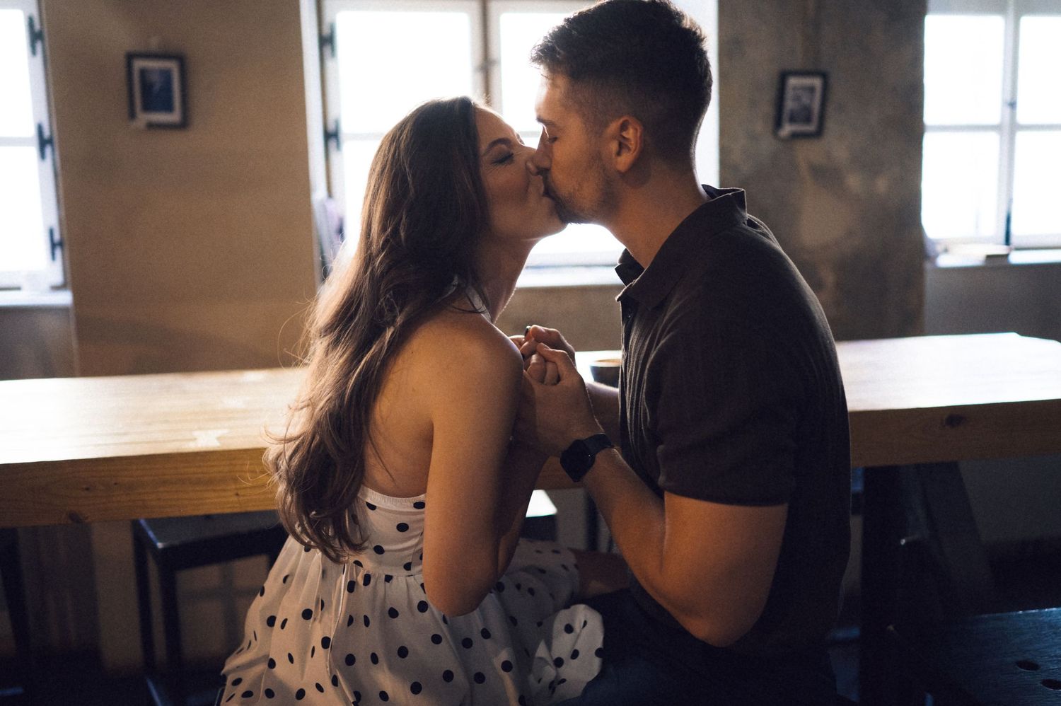 A couple shares an intimate moment together in a dimly lit restaurant setting.