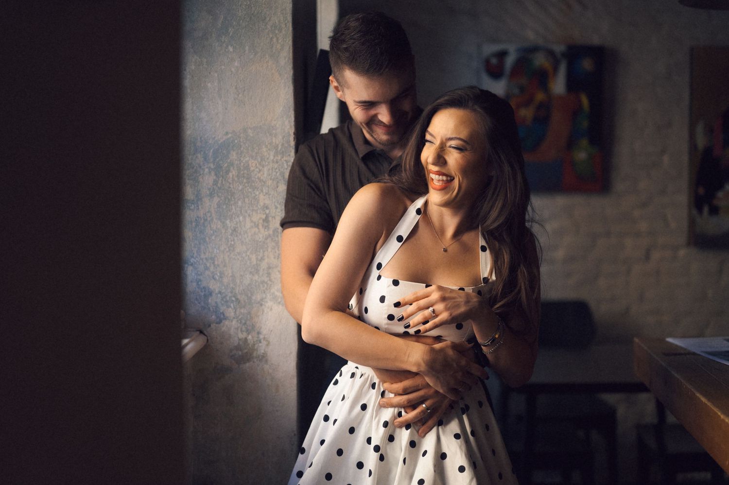 A couple shares a romantic dance in a dimly lit room, creating an intimate and joyful moment together.
