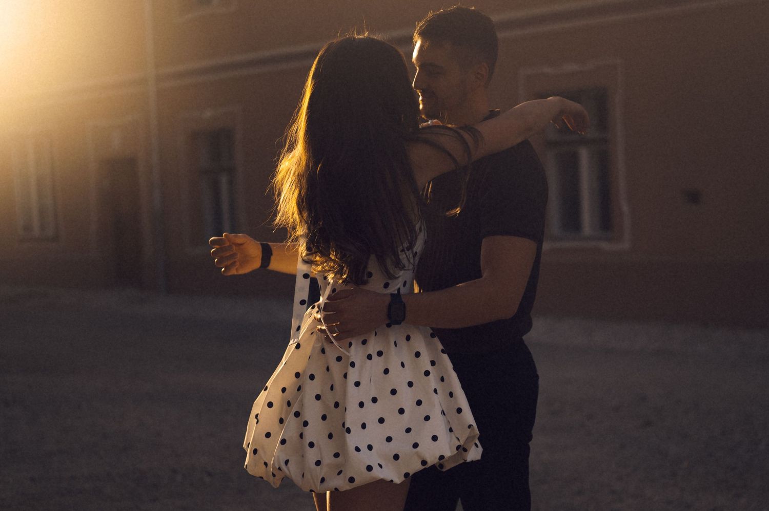 A couple dances together in an intimate embrace on a dimly lit dance floor during a romantic evening.