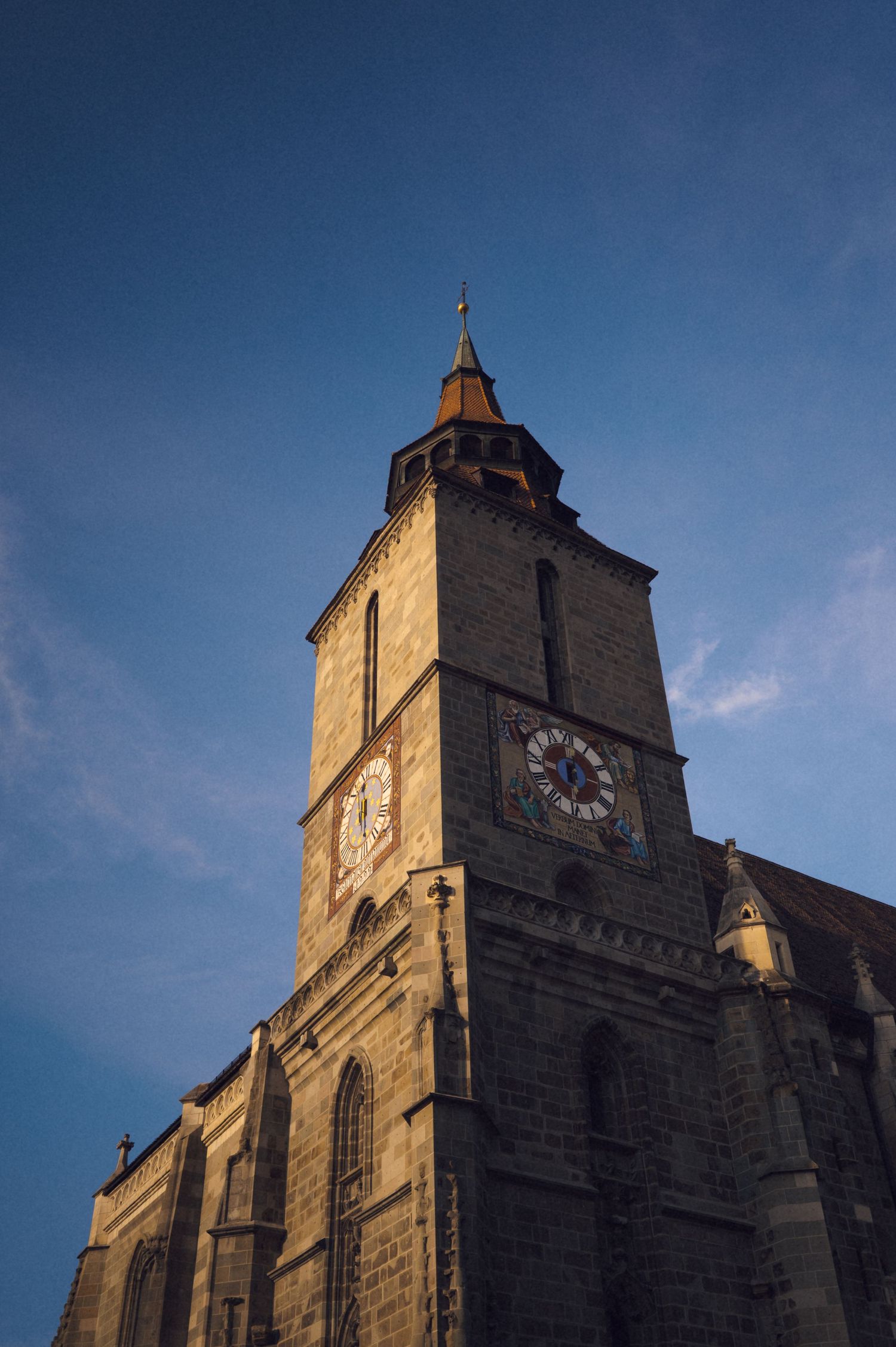 Historic stone church facade with clock tower photographed at different angles against a deep blue sky at sunset.