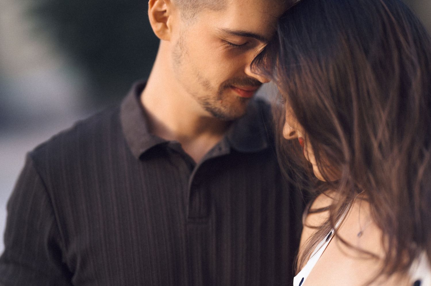 A couple shares a romantic kiss while embracing in a close-up black and white photograph.