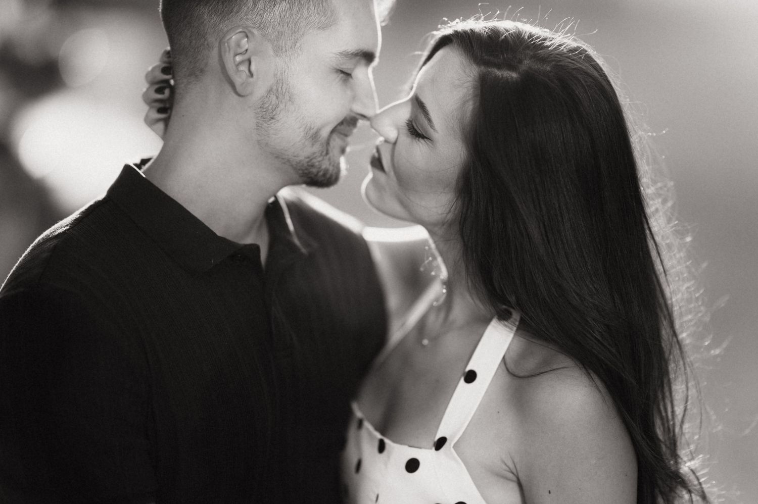 A romantic black and white close-up photo of a couple about to kiss in soft lighting.
