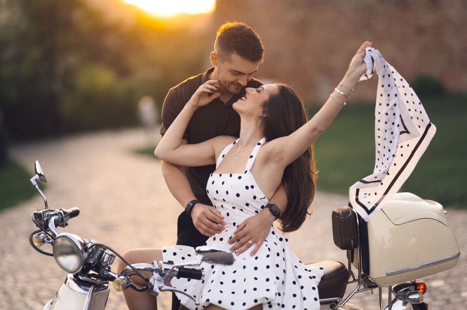 A romantic couple shares tender moments on a motorcycle during a golden sunset photoshoot.