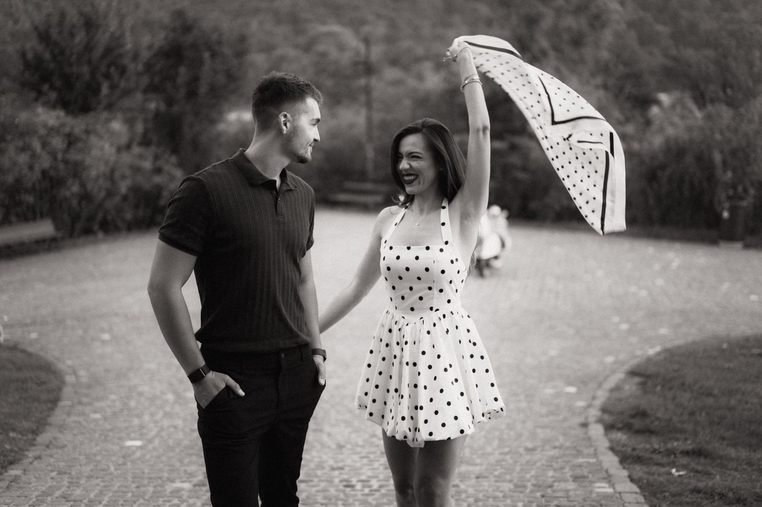 A couple in black and white polka dot attire shares romantic moments together in an outdoor garden setting.
