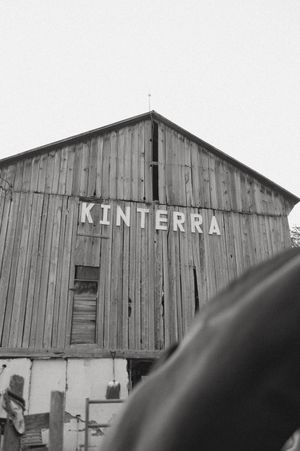 A black and white photograph of a weathered wooden barn with 'KINTERRA' text on its facade.