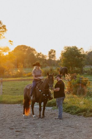 People with horses in a field during golden hour sunset.