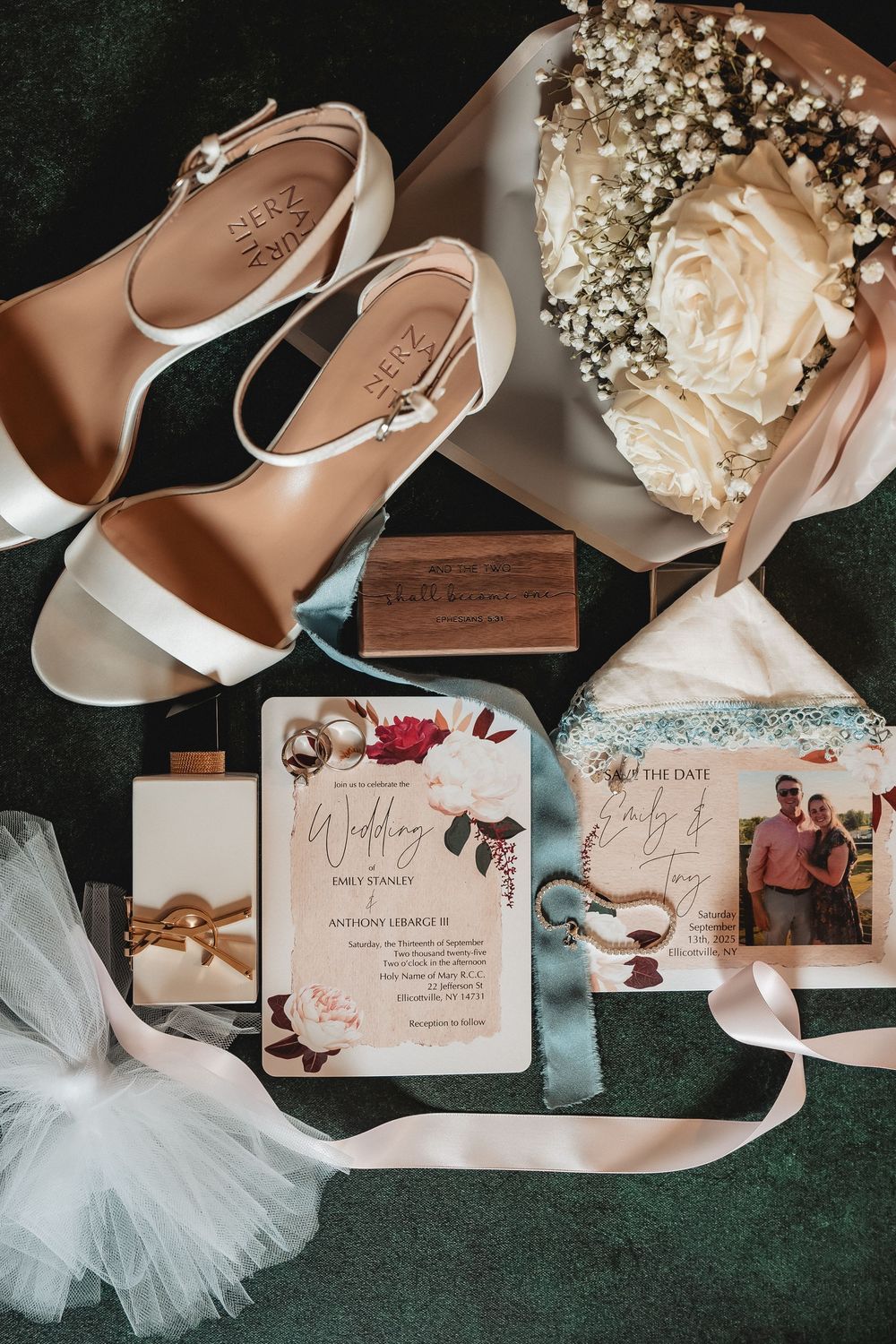 Wedding details flat lay featuring bridal shoes, invitation cards, and baby's breath flowers on dark green velvet background.