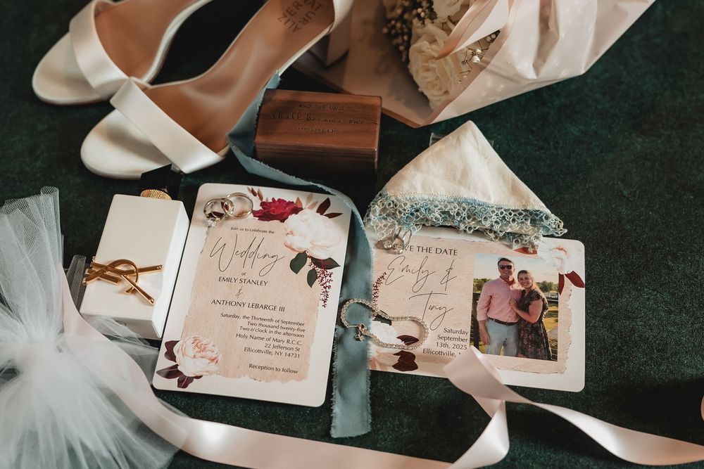 Wedding invitation cards arranged with wedding rings and elegant details on a dark surface.