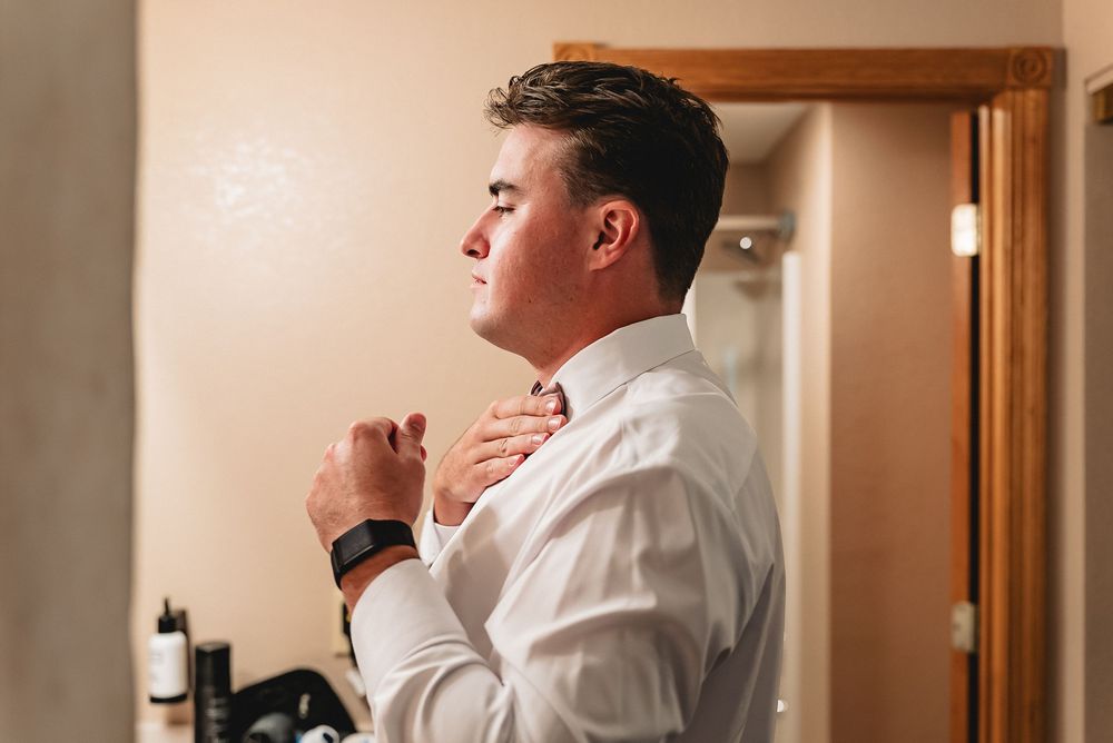 Professional dressed in white chef coat makes a hand gesture while turned toward the side in a softly lit setting.