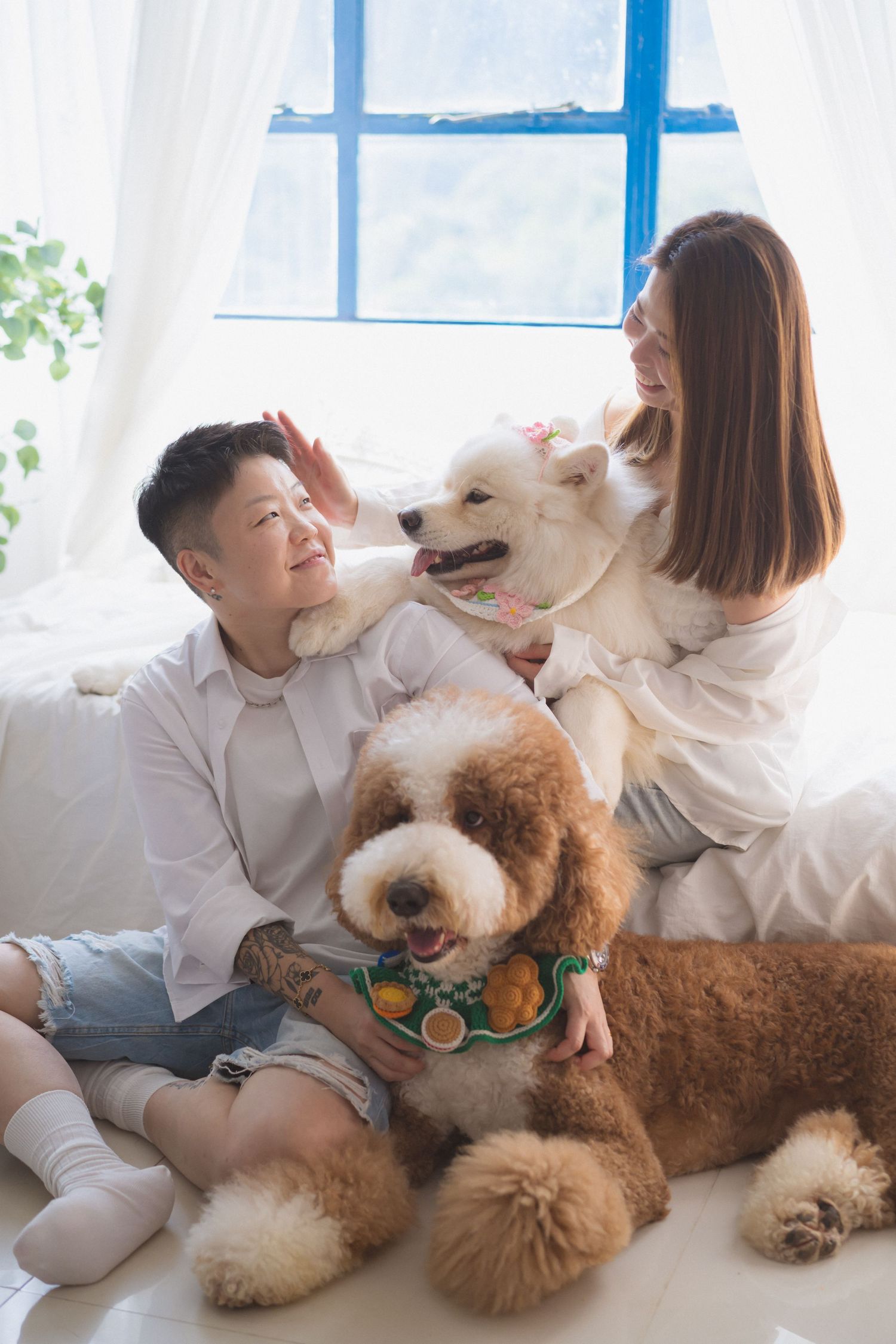 A couple embraces intimately by a sheer white curtained window during a romantic wedding day photoshoot.