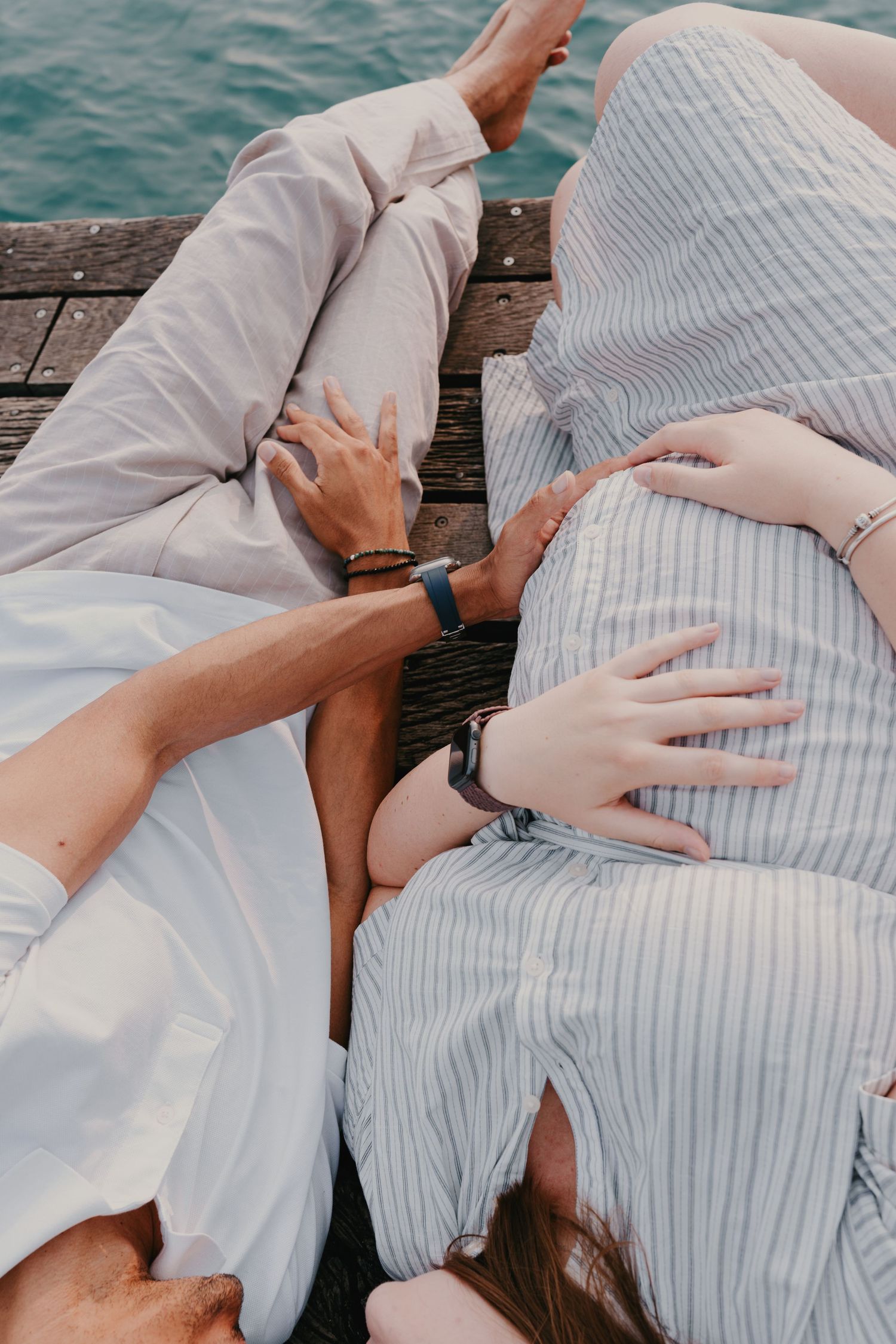 Couple allongé et partageant un moment de complicité sur le ponton à Talloires lors d'une séance photo grossesse.