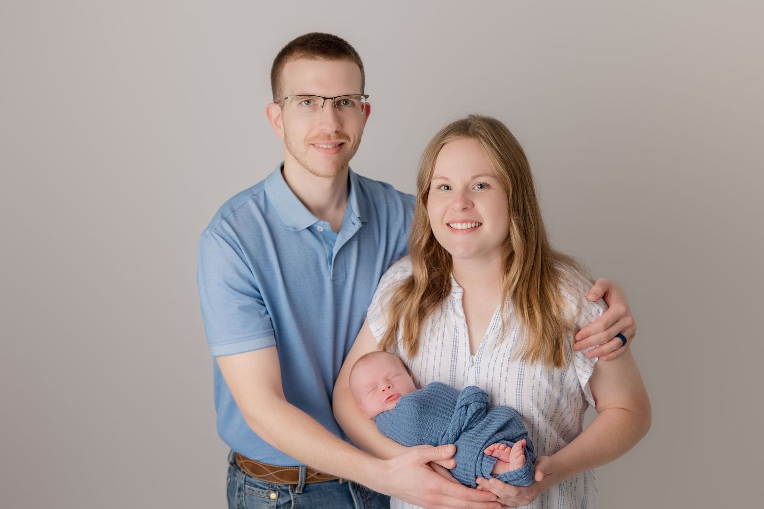 A couple in blue and white outfits share tender moments during a photo session.