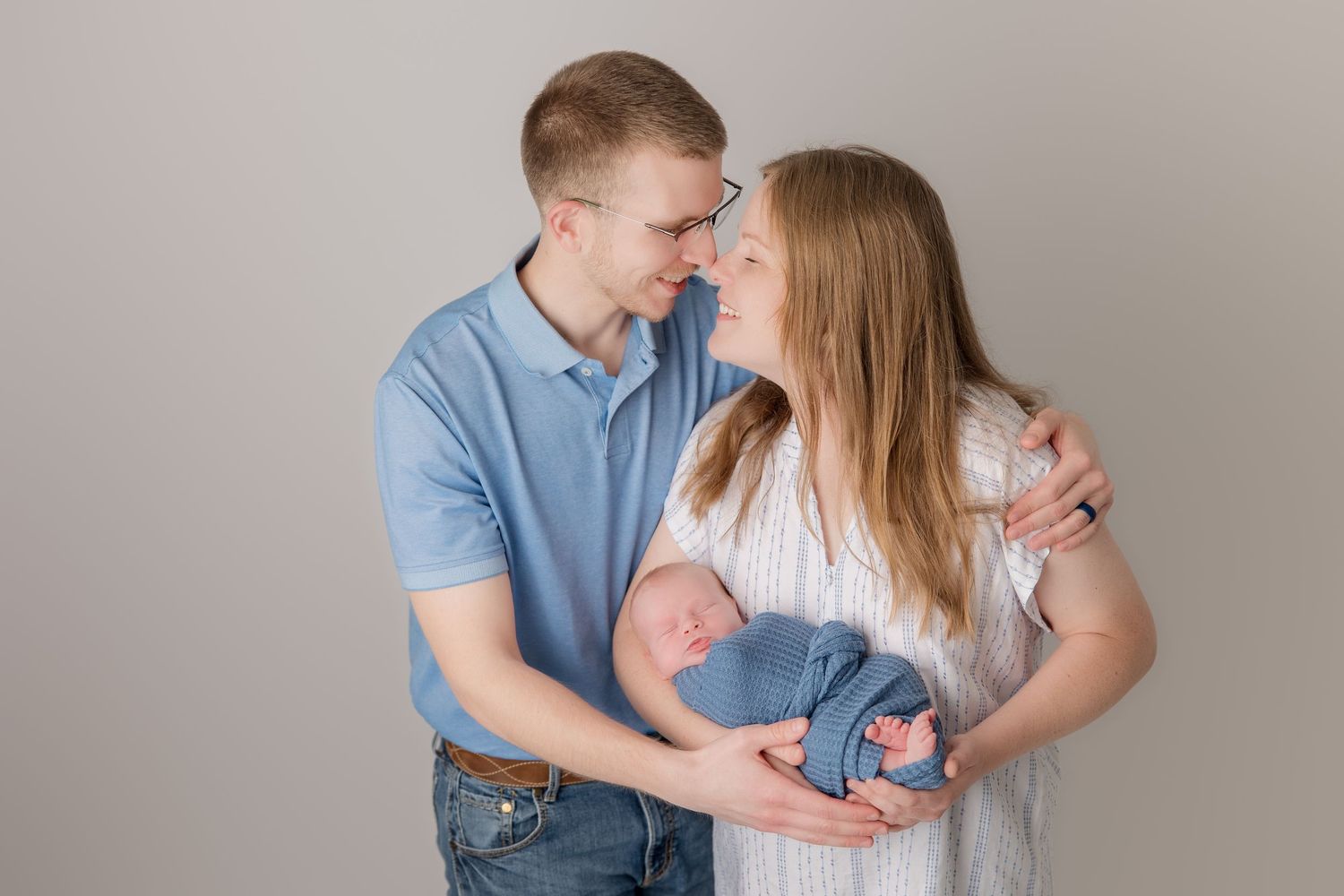 A loving couple in coordinating blue and white attire share intimate poses during a portrait session.