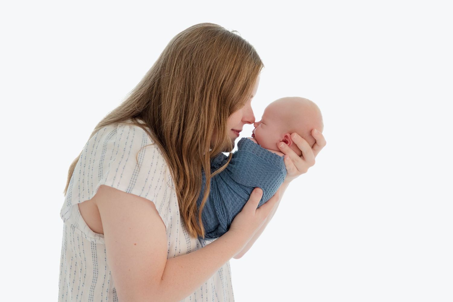 Family portrait showing parents gazing adoringly at their baby in a bright white studio.