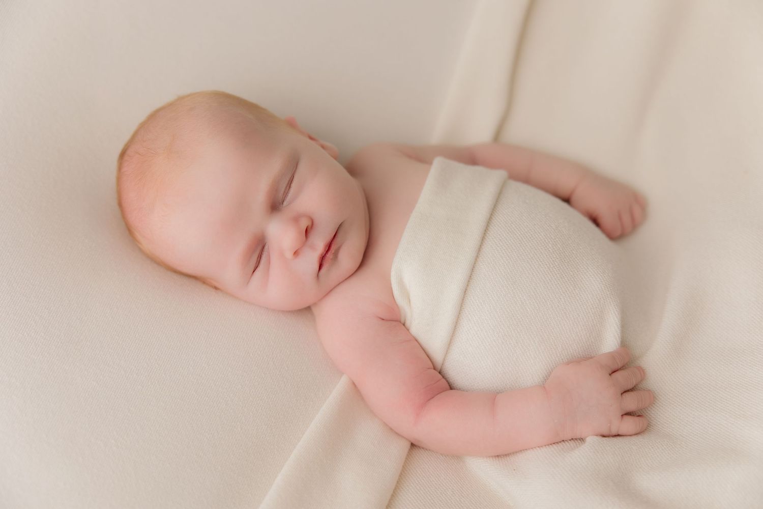 A series of tender moments showing close-up photos of newborn baby feet, hands, and sleeping poses on white fabric.