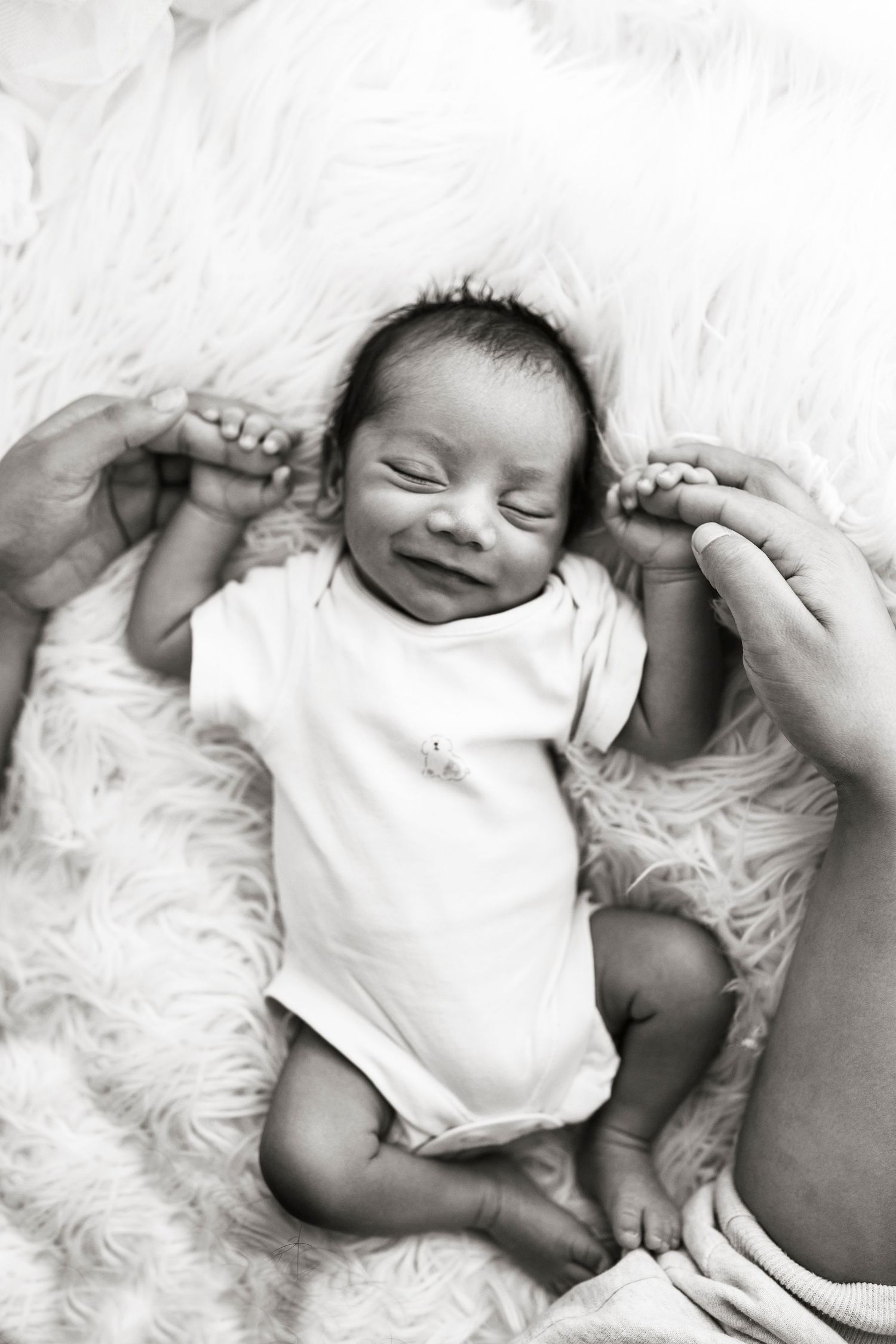 Newborn baby holding parents hands and smiling by Little Wonderland Photography Widnes Cheshire