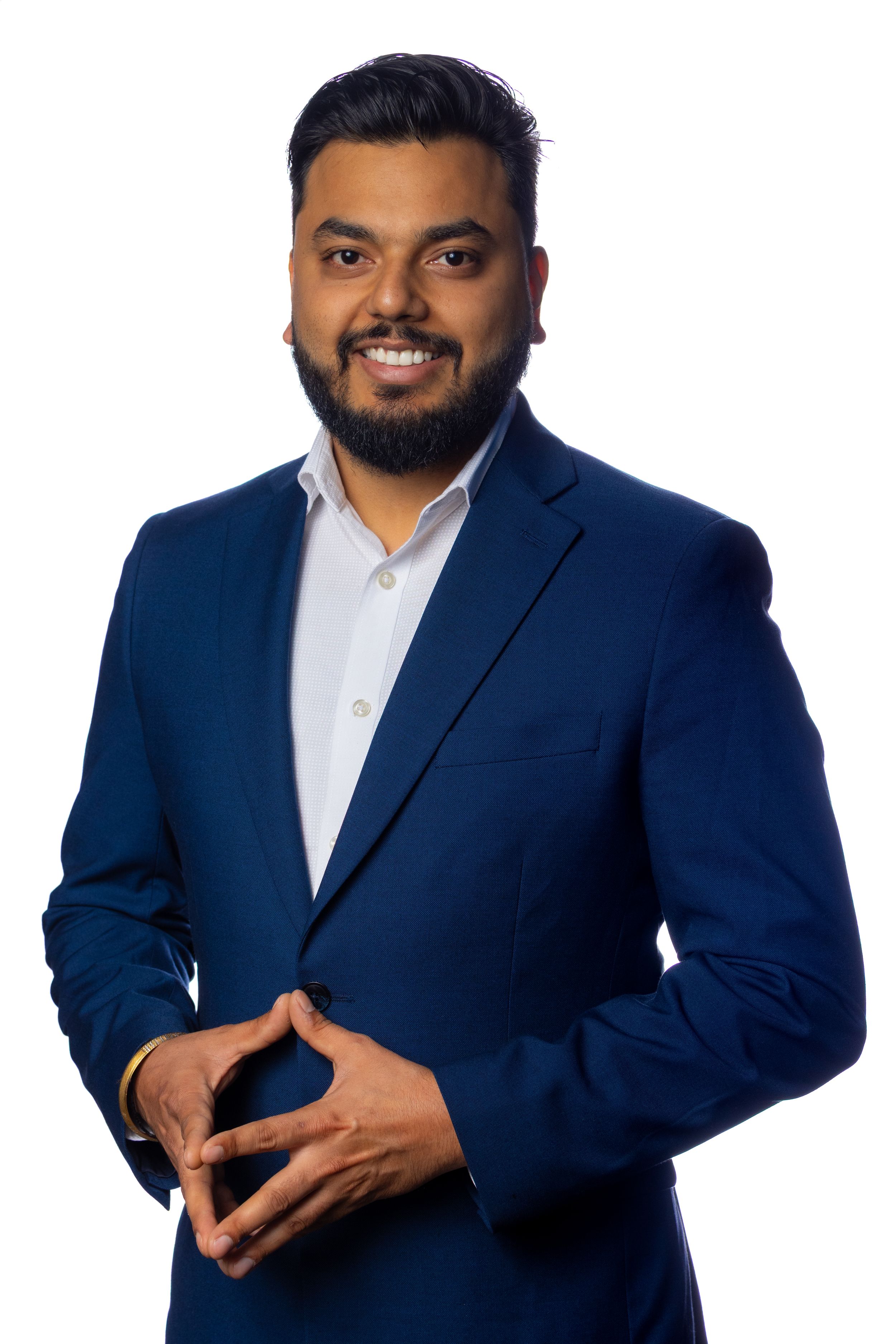 Professional portrait of a person in a navy blue suit and white shirt smiling against a light background.