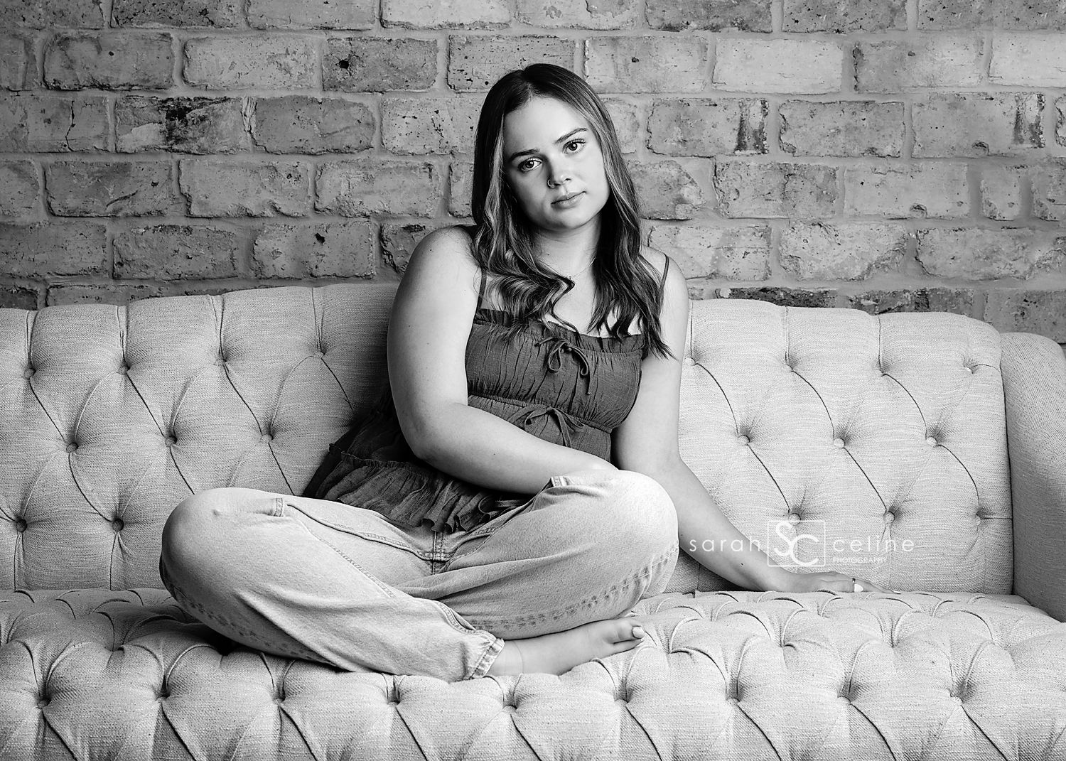 Black and white photo series showing a person lounging in different relaxed poses on a tufted sofa against a brick wall.