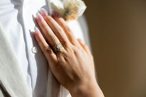 Close-up view of hands wearing white medical gloves holding a stethoscope against a white background.