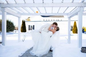 A couple shares a romantic kiss under an elegant white pergola during their wedding celebration.