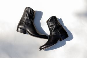 Black leather wedding boots photographed on white background.