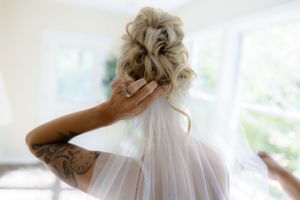 An elegant updo hairstyle with a delicate white veil for a wedding day look.