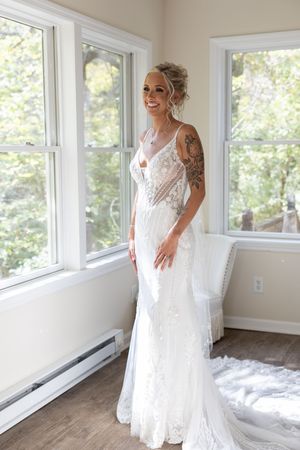 A full-length view of a fitted lace wedding gown with delicate straps in natural light.