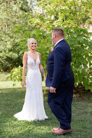Sweet first look moment captured in a garden with green foliage backdrop.
