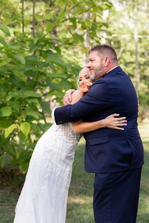 Joyful embrace during wedding first look moment in outdoor garden setting.