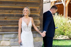 Wedding first look photos taken against rustic log cabin exterior.