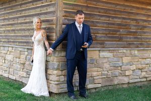 Candid first look moments captured against stone and wood cabin wall.