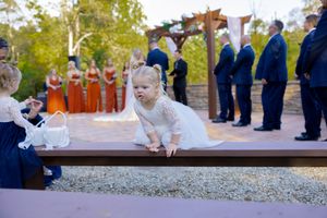 Wedding ceremony in progress at rustic outdoor venue with stone and wood pergola.