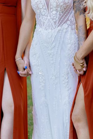 Close-up detail of white lace wedding dress with intricate beading and embellishments.