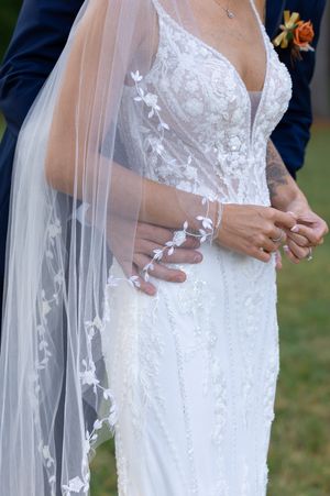 Close-up details of delicate lace appliques on white wedding dress and veil.