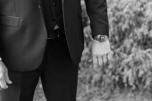 Row of groomsmen in black suits standing together at outdoor wedding.