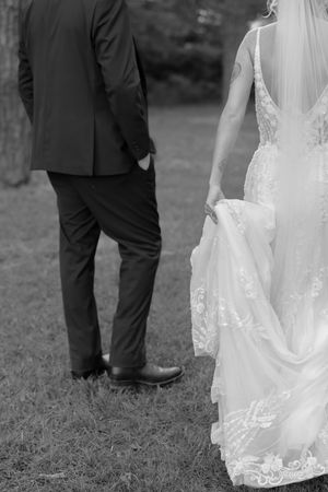 Close up of white lace wedding dress details and formal suit.