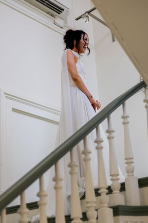 White-dressed figure descends vintage staircase in artistic wedding photography shot.